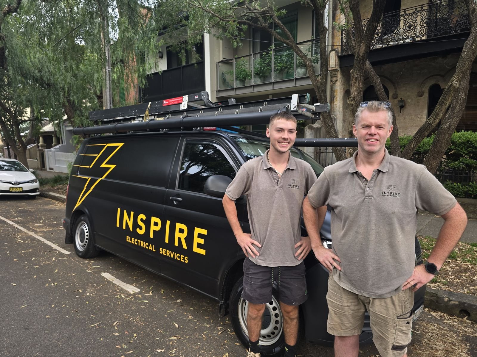 Brían and Brendan standing beside the black Inspire van