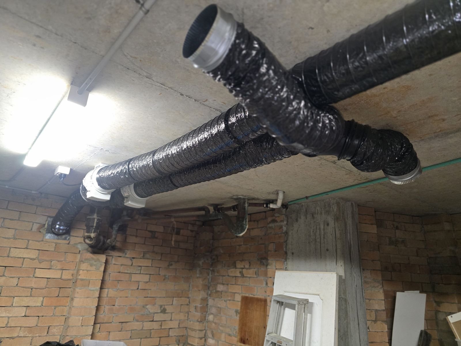 Two black ducts fixed to a concrete slab soffit