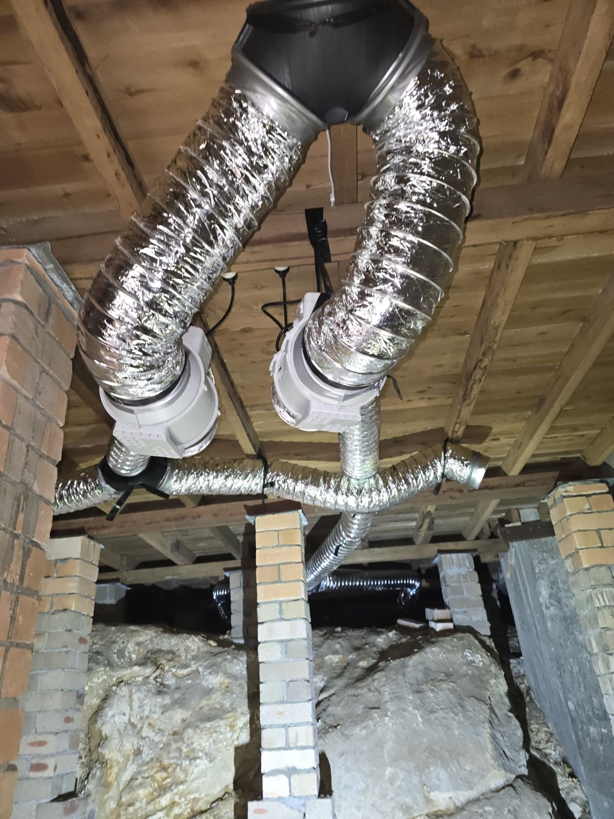 Ducting worked around sandstone and brick under a floor