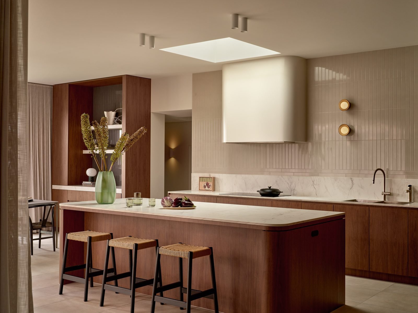 Walnut kitchen island under a skylight, with a curved range hood, ceiling spotlights and two round wall lights