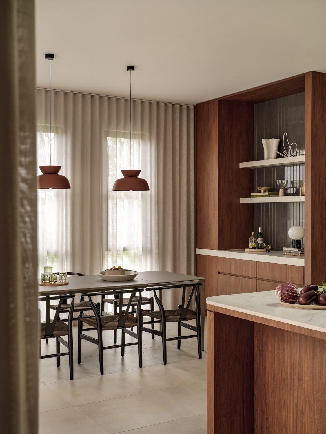 Dining table with two rust-coloured pendants above it and open shelving beside