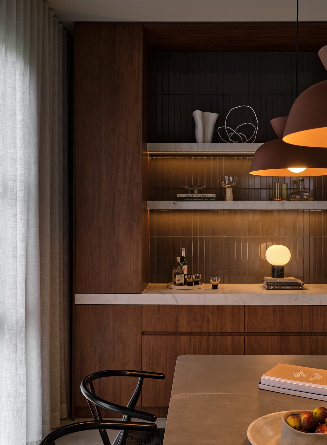 Open shelves with strip lighting under each shelf, a table lamp and a rust pendant in front