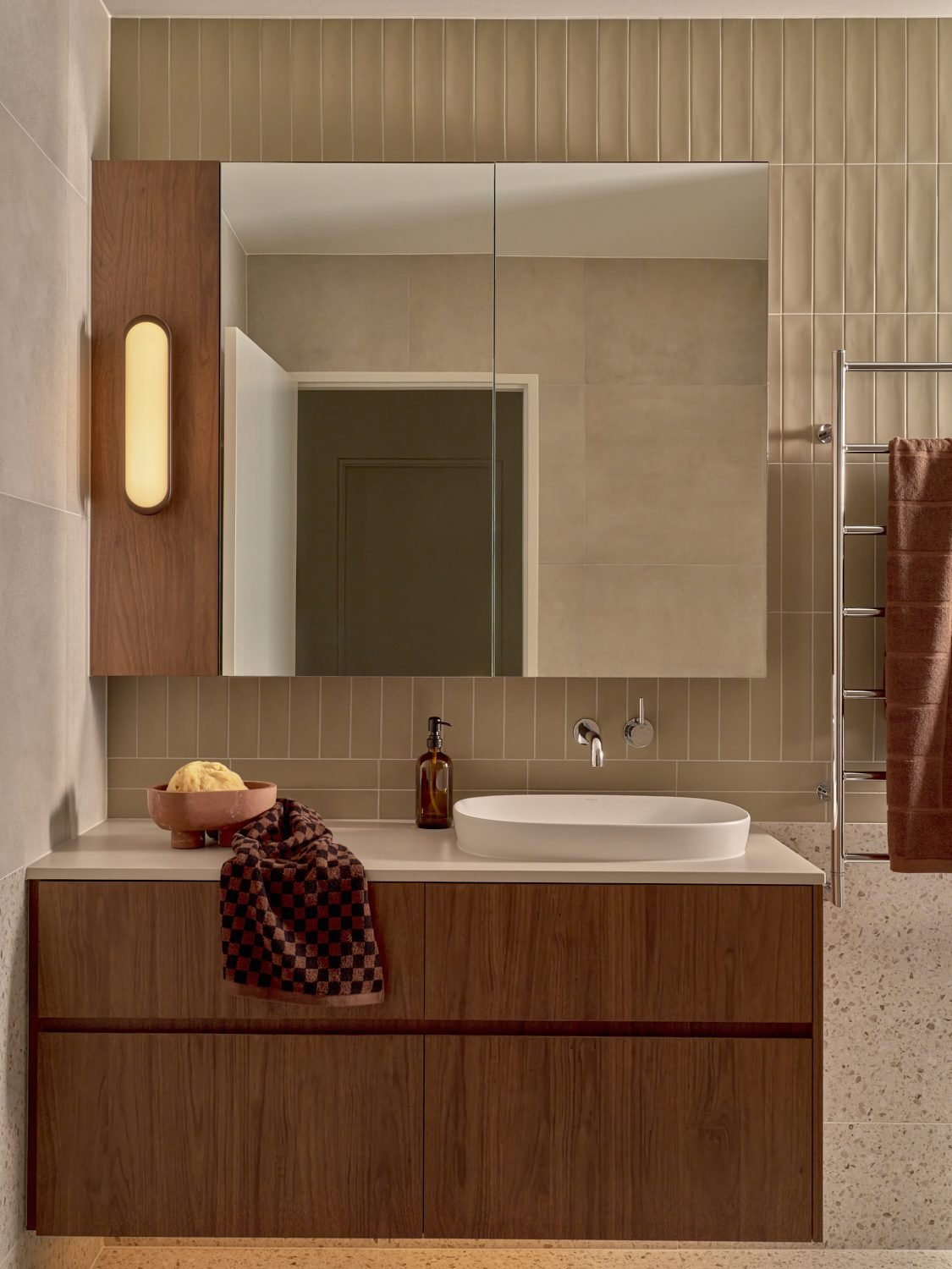 A second vanity with a pill-shaped wall light beside the mirror cabinet