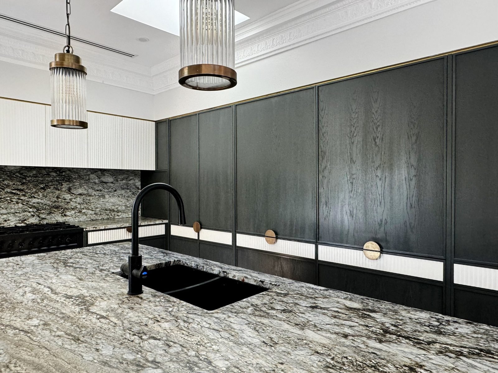 Glass pendants in front of the stone splashback and cooktop wall
