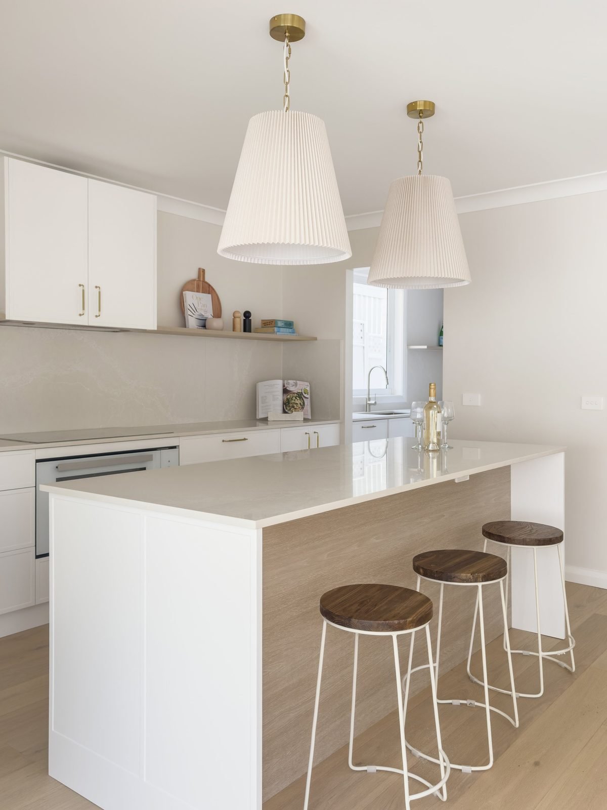 Two pleated pendants on brass fittings over the island, seen from the kitchen