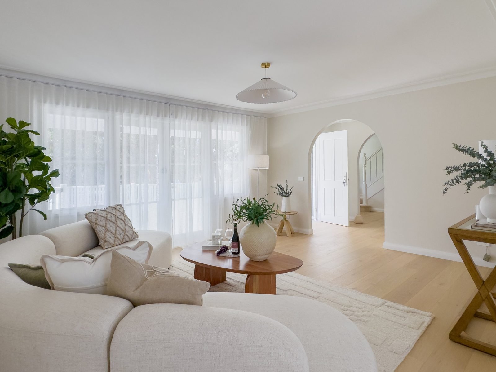Lounge room with a pendant light and an arched doorway through to the hall
